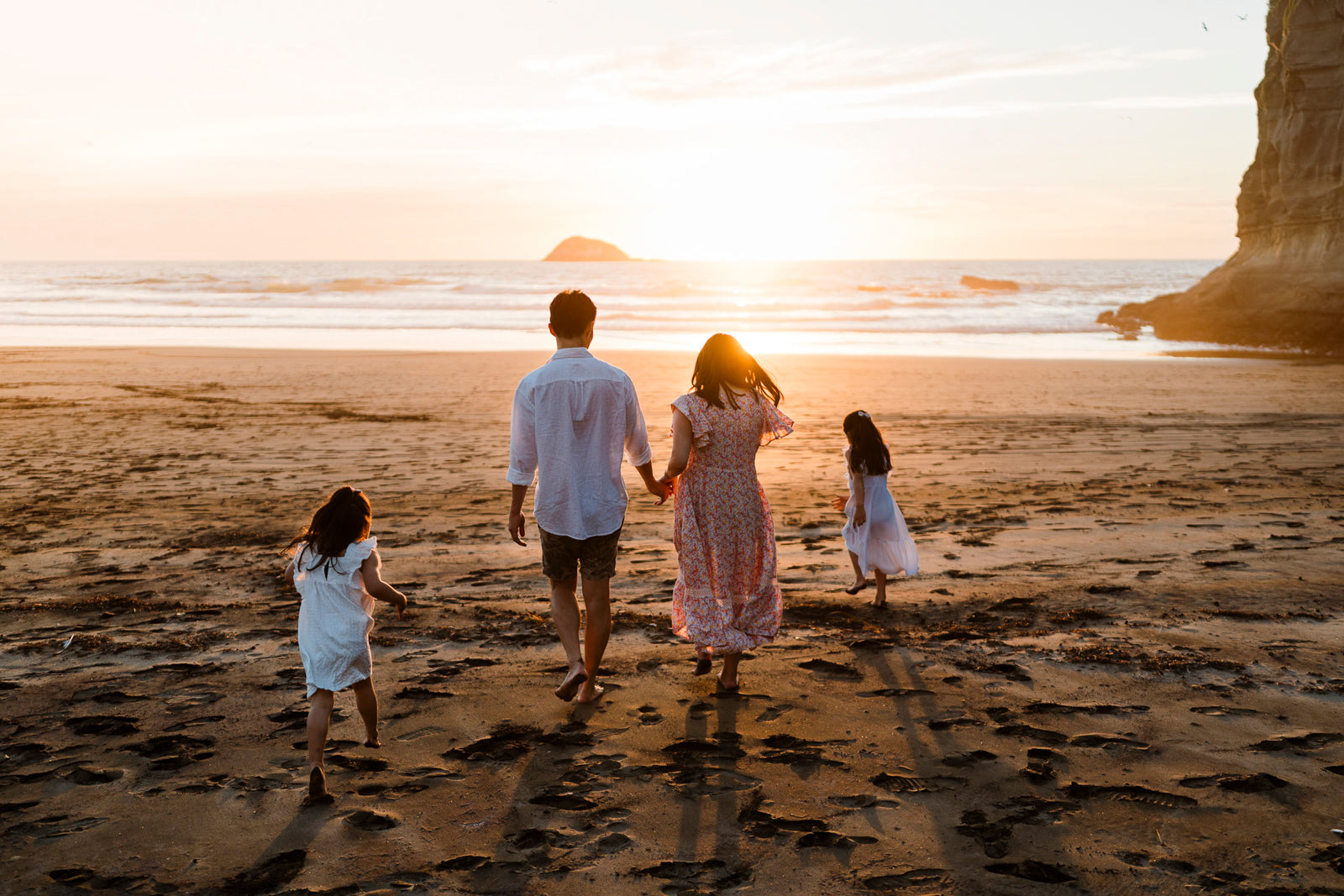 Family of 4 being photographed at sunset at Maori Bay, Muriwai
