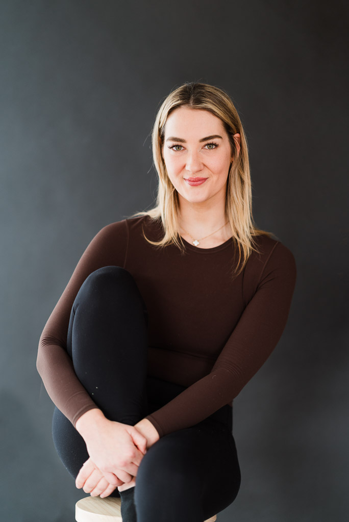 Creative personal branding photo with dramatic flash lighting, black backdrop, and minimalist style.