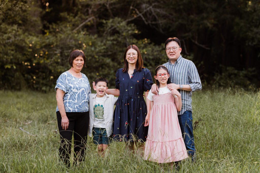 Family of five, including Nana, posing together in Riverhead Forest at sunset – West Auckland family photography by Auckland photographers.