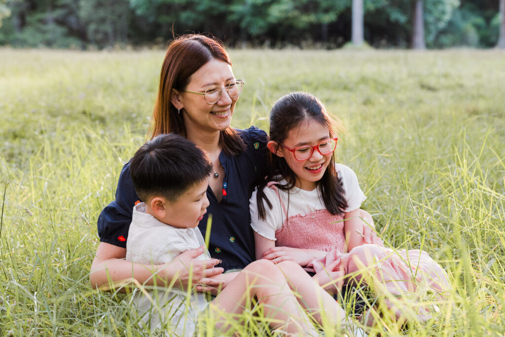 Mum with children smiling together in Riverhead Forest at sunset – warm family portrait in West Auckland.