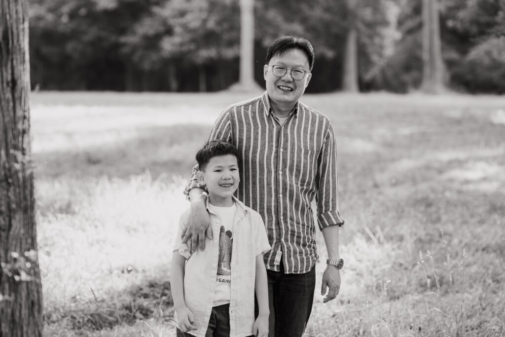 Dad and son sharing a quiet moment in Riverhead Forest at sunset – intimate family portrait by Auckland family photographers.