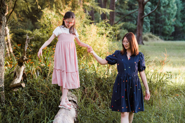 Mum walking daughter along a log in Riverhead Forest during a golden hour family session – West Auckland family photographers capturing connection.