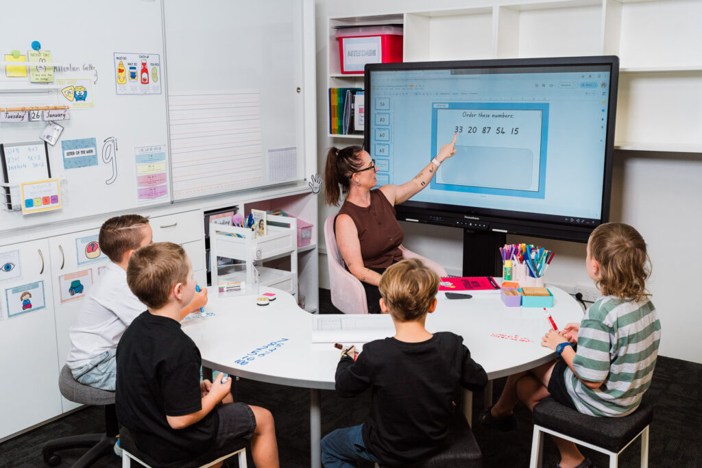 Group of children engaging with Mrs Priestly’s educational tools at a desk, captured as brand photography in Auckland.