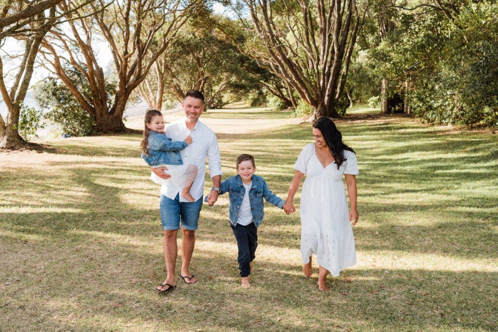 Side profile of family walking together at golden hour, with soft sunlight in the background – candid family moments at Cornwallis Beach.