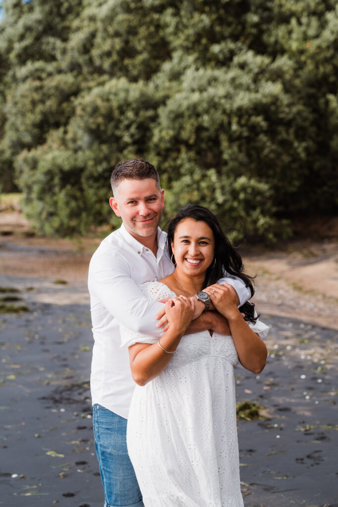 Mum and dad sharing a quiet moment together during their family shoot at Cornwallis Beach – relaxed and romantic portrait by Auckland family photographer.