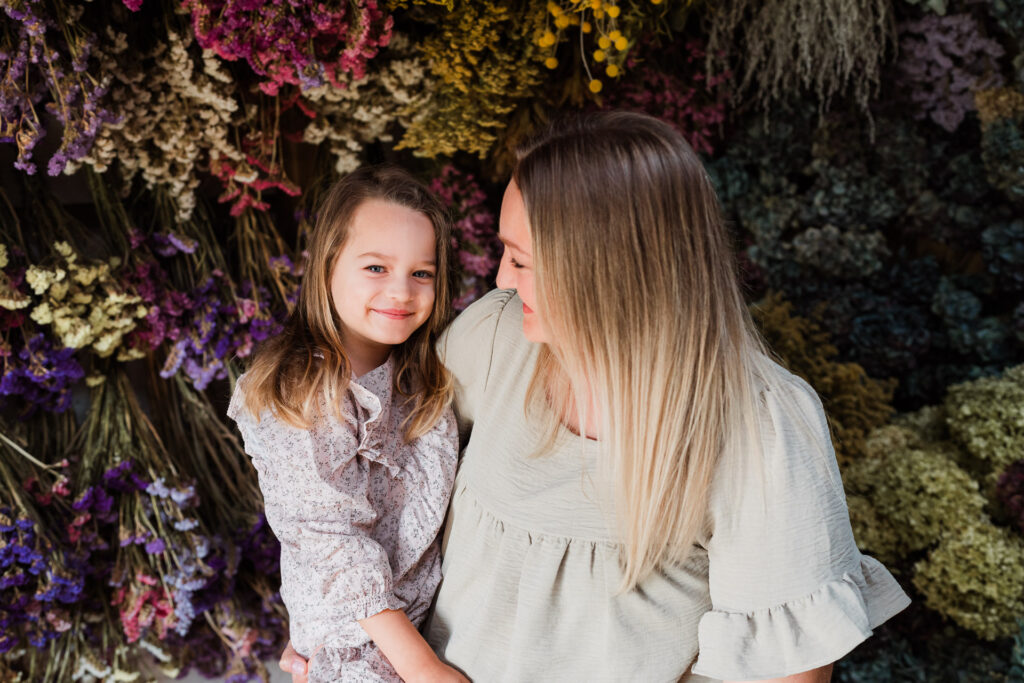 Mum holding toddler close during Auckland floral mini session, captured in natural light by Wonderferris.