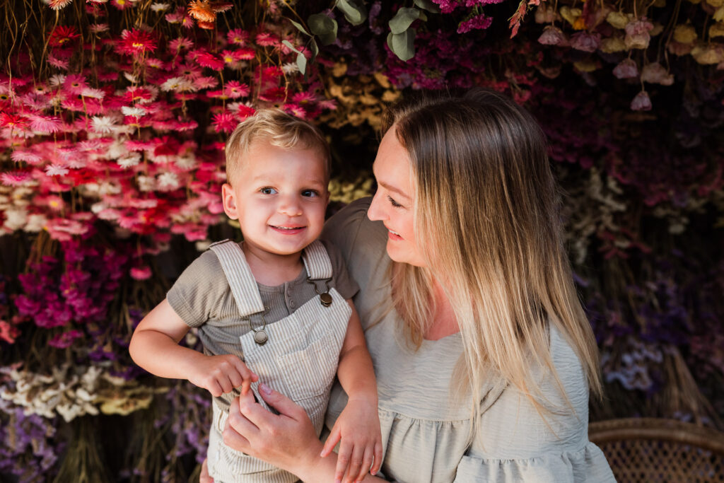 Candid photo of mum and toddler laughing together inside Ella May Florals’ florist shed in Taupaki.