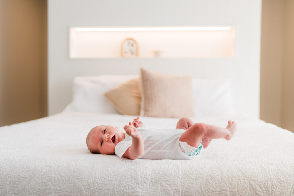 Newborn baby lying peacefully on the bed in a natural lifestyle shoot at home, Auckland family photography.