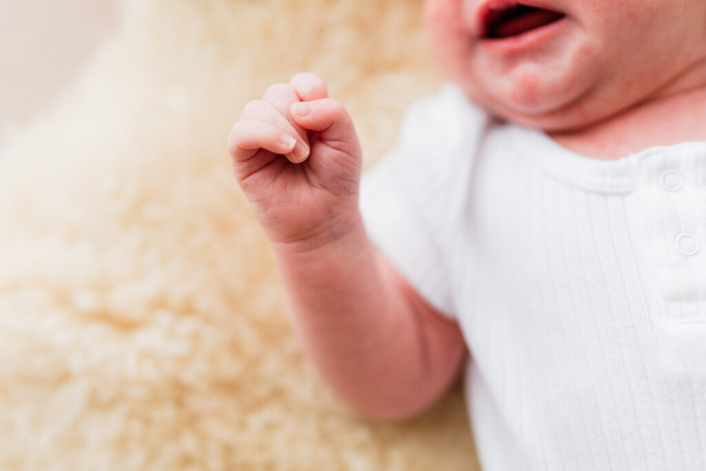 Close-up of newborn’s hand holding dad’s finger during a lifestyle session at their Auckland home.