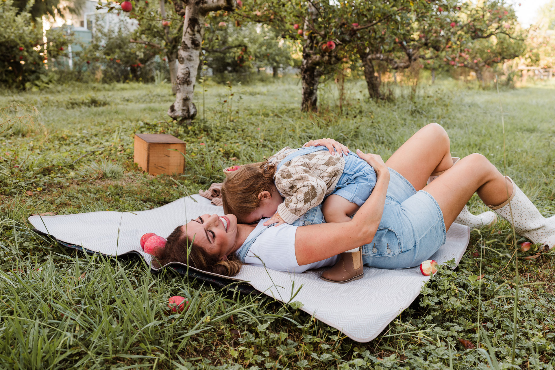 Candid photo of a family snuggling together at early morning orchard shoot in NorthWest Auckland.