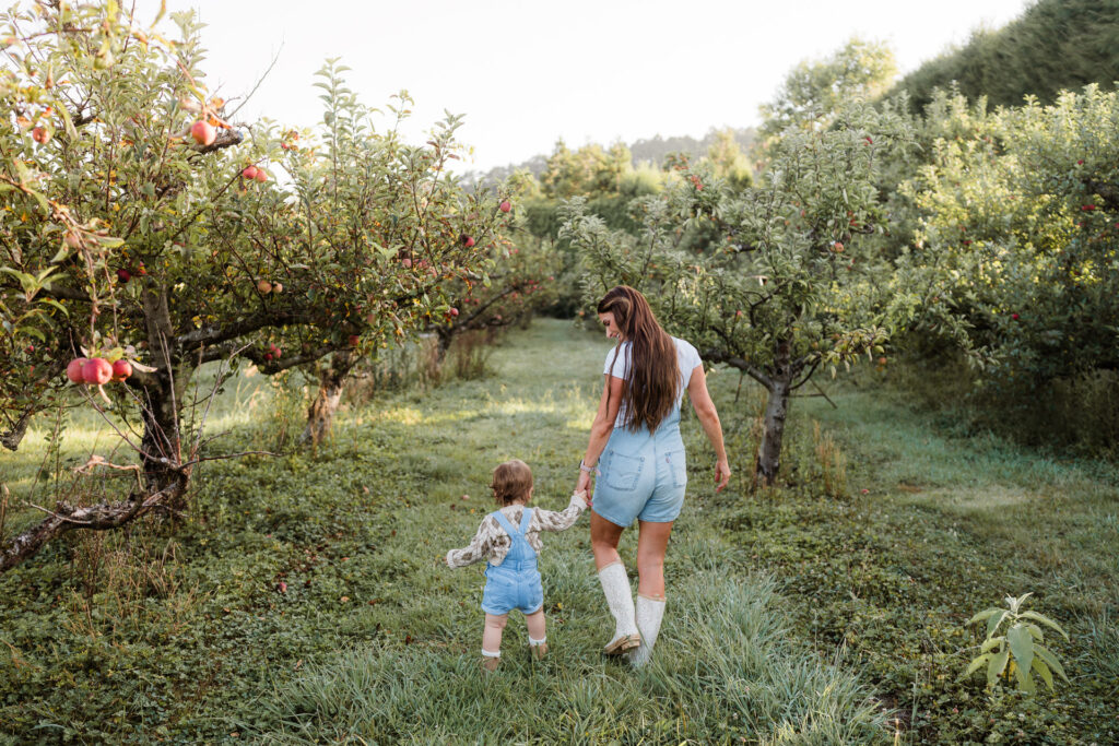 Smiling child running through orchard rows during Auckland seasonal mini photography session.