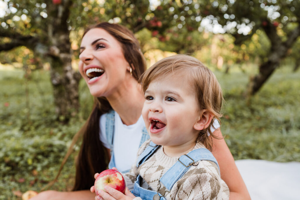 Mother and son laughing together in soft orchard light during Auckland mini session.