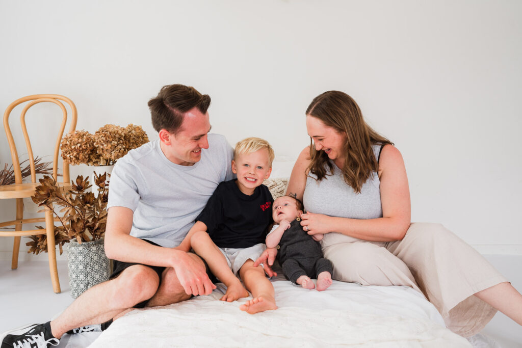 Family of four lying together on the bed during a mini session at Wonderstudio, Kumeu – West Auckland family photographers.