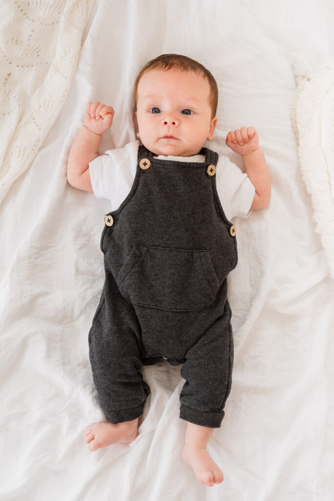 Newborn baby boy lying on the bed, looking directly at the camera during a newborn shoot at Wonderstudio, West Auckland.