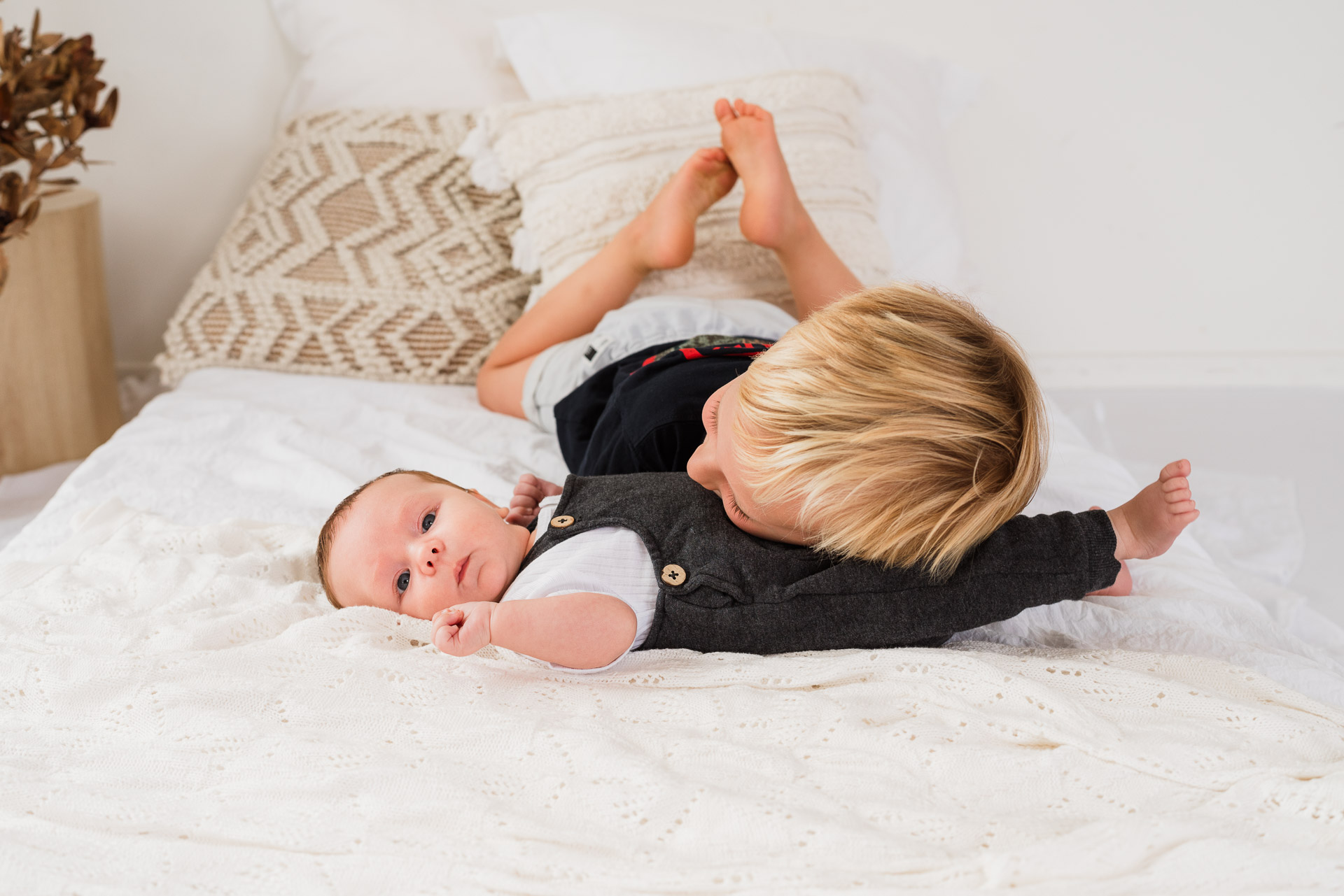 Older brothers cuddling together on the bed during a family mini session at Wonderstudio in Kumeu – sibling connection in Auckland family photography.