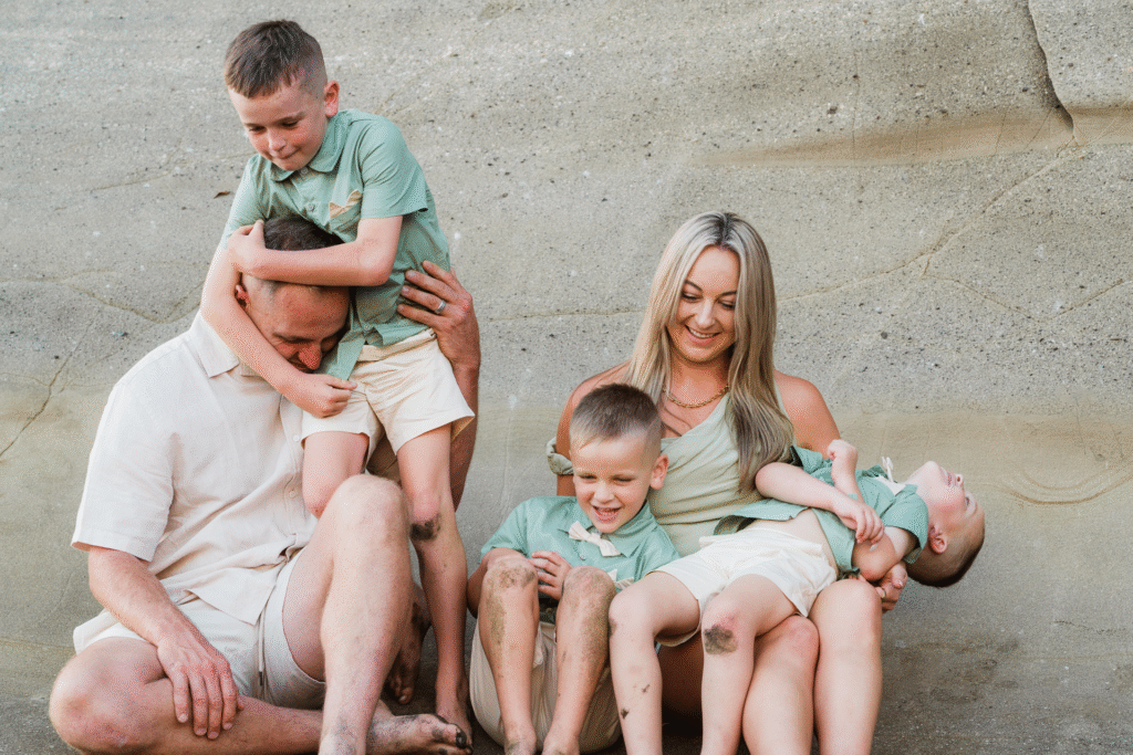 Candid family moment with laughter and connection at Maori Bay during golden hour.