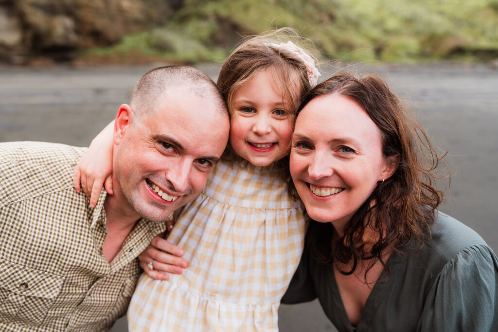 Family laughing together at sunset during a beach mini shoot in Auckland’s Maori Bay.