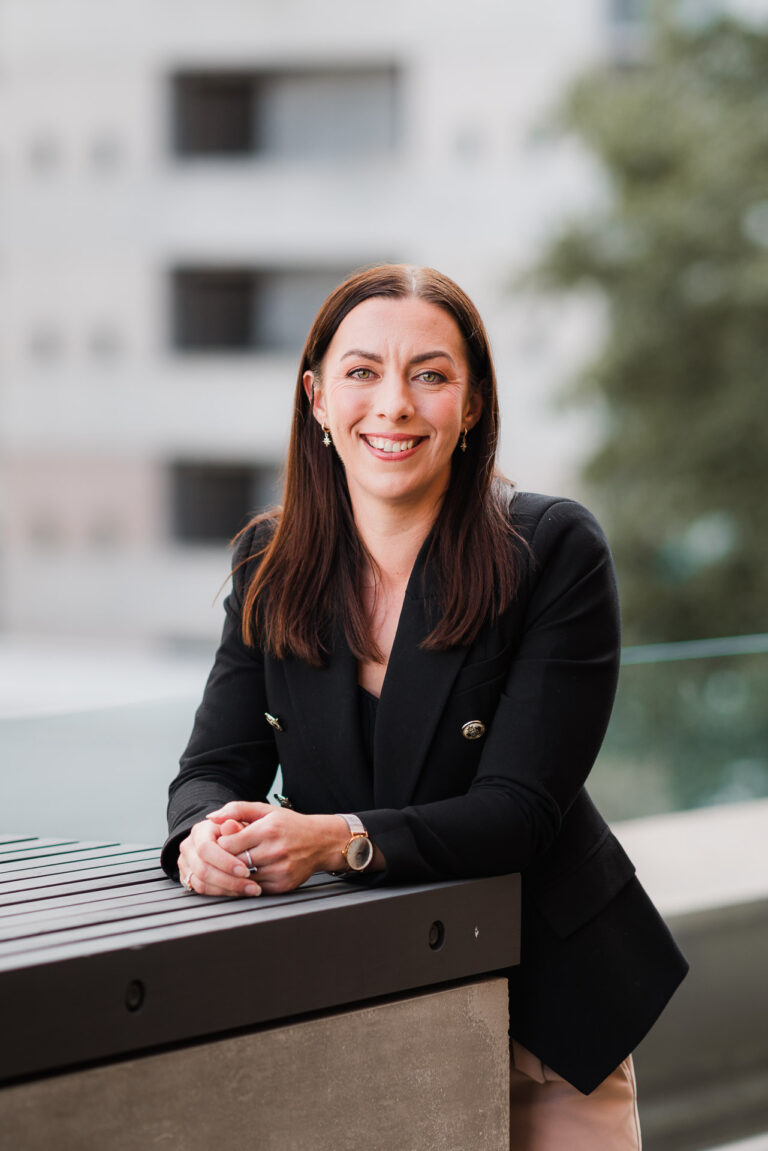 Co Legal team members smiling in a relaxed team portrait on a city rooftop.