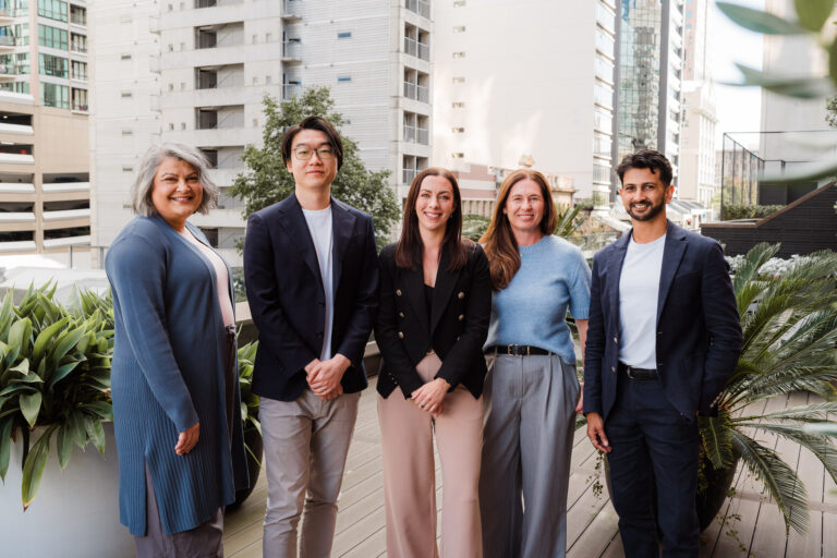 Group photo of the Co Legal team on a rooftop overlooking the Auckland city skyline.
