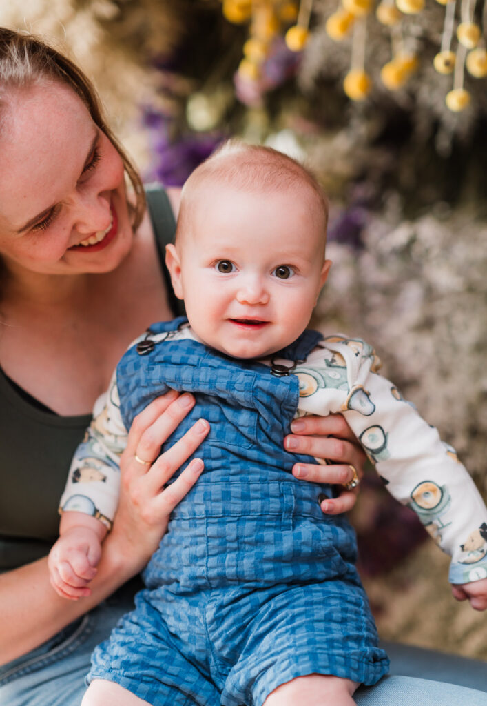Warm, close-up image of mum and baby in a soft floral setting during mini photography session.