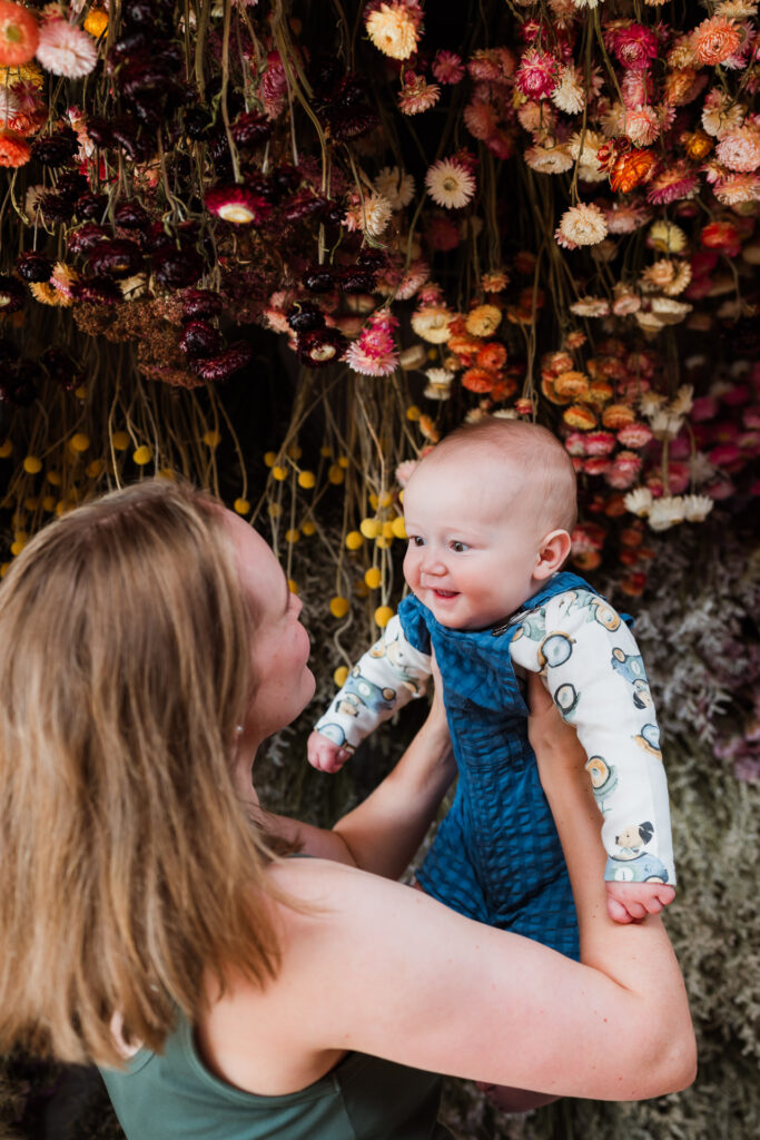 Mum smiling at baby during Auckland mini session with dried flowers, captured at Ella May Florals.