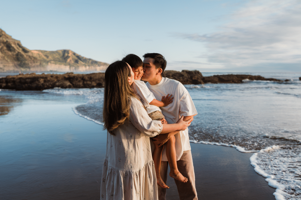 Candid beach family portrait during golden hour at Muriwai, taken by Auckland mini photographers Wonderferris.