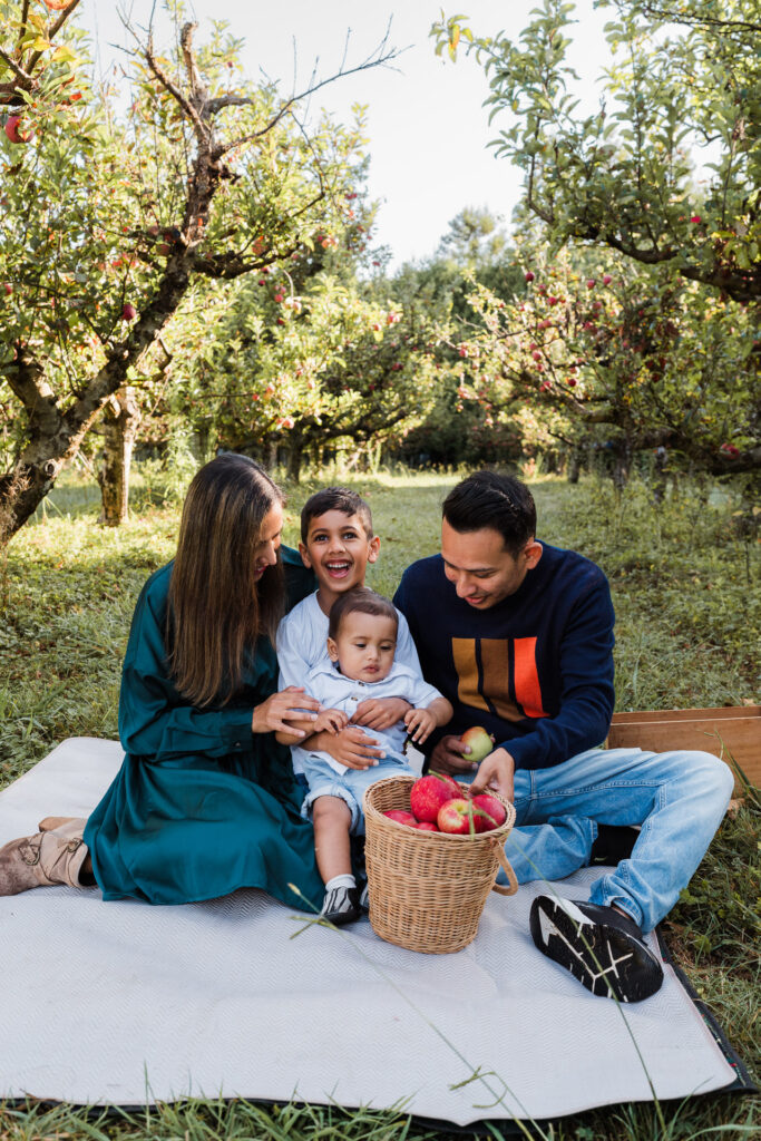 Family cuddling during an early morning mini session in a NorthWest Auckland orchard, photographed by Wonderferris.