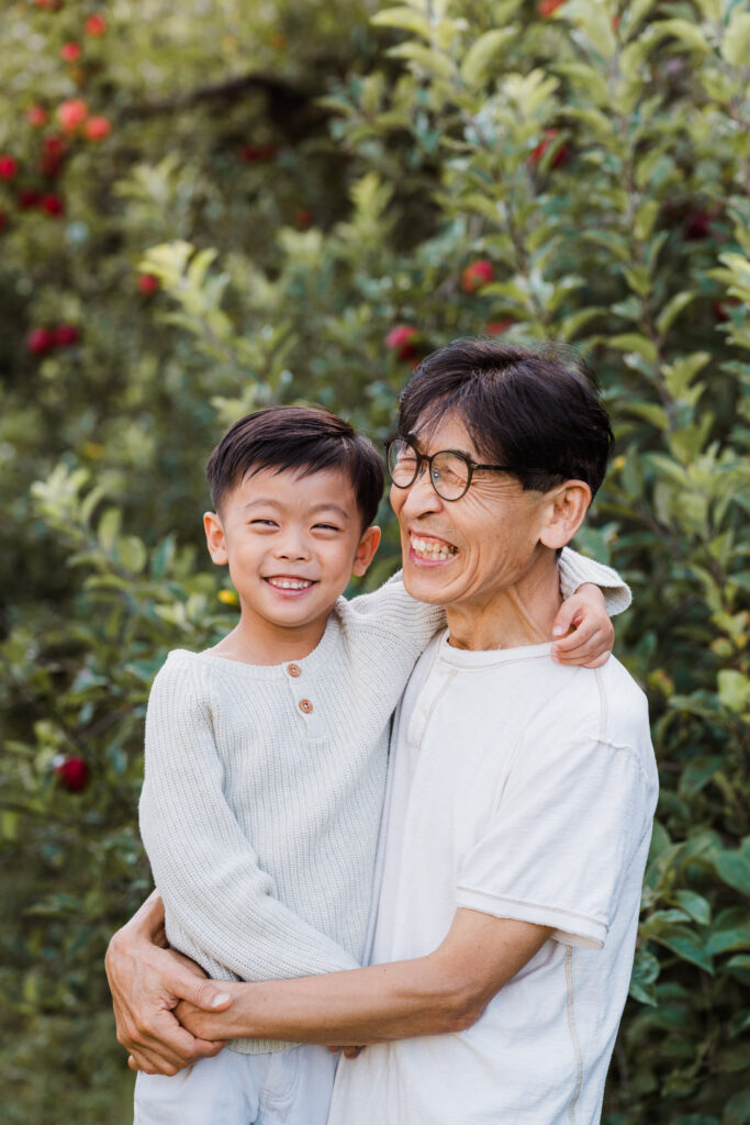 Granddad lifting his grandson in the air during a joyful orchard mini shoot in Auckland, photographed by Wonderferris.
