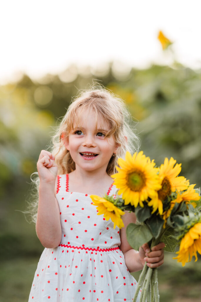 Young girl smiling in the sunflower field at Franklin Farms during a Wonderferris Auckland mini session.