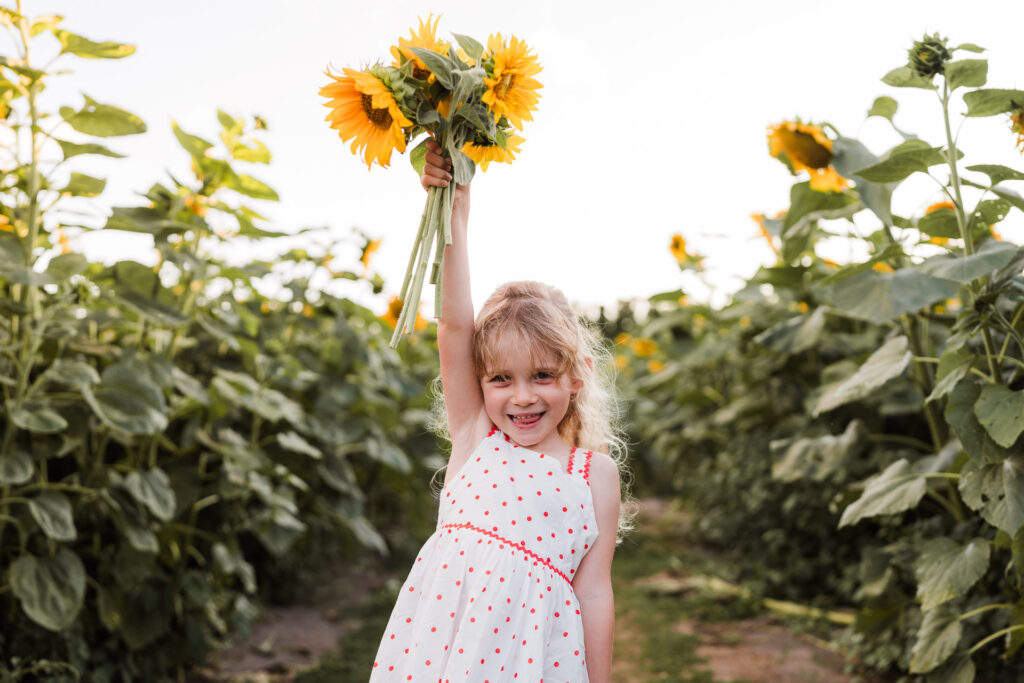 Candid photo of girl twirling in the sunflower field during a golden hour mini session in Auckland.