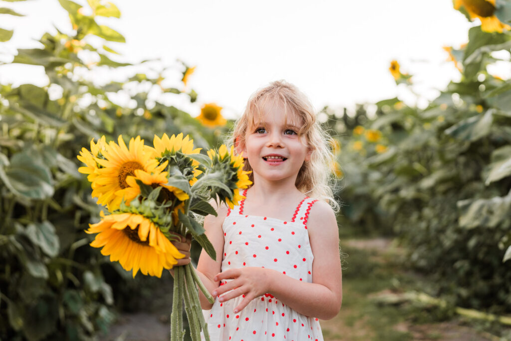 Joyful portrait of a young girl laughing among sunflowers at Franklin Farms during an Auckland mini session by Wonderferris.