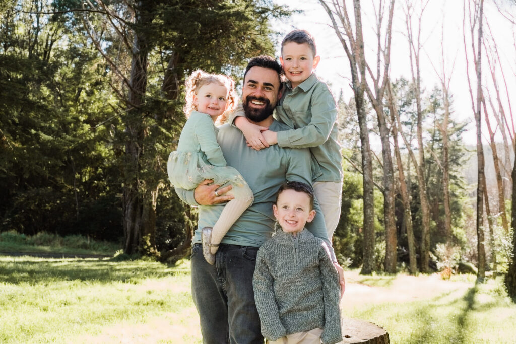 Parents and two children standing side by side in the forest, looking at the camera — Wonderferris family photography