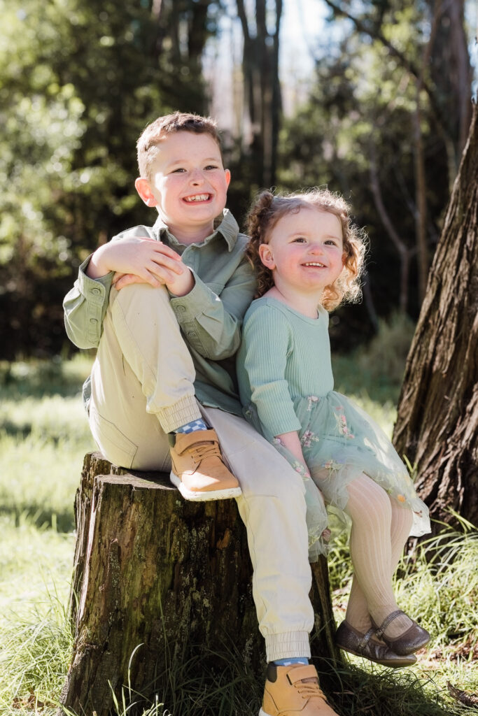 Two siblings hugging in Riverhead Forest, smiling at each other — family photography by Wonderferris