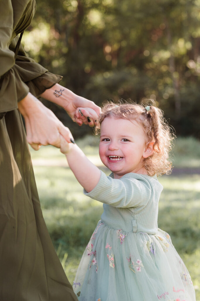 Young girl standing alone in Riverhead Forest, smiling softly — portrait by West Auckland family photographer