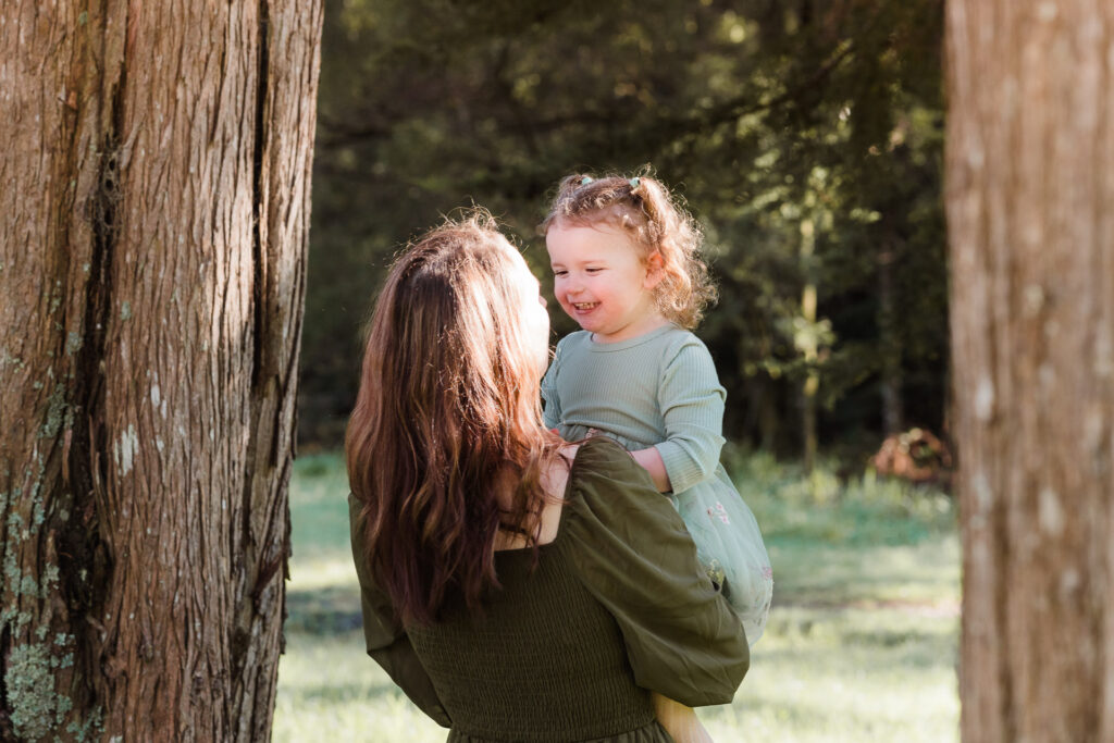 Mother and daughter laughing together in the forest light — captured by Kumeu family photographers