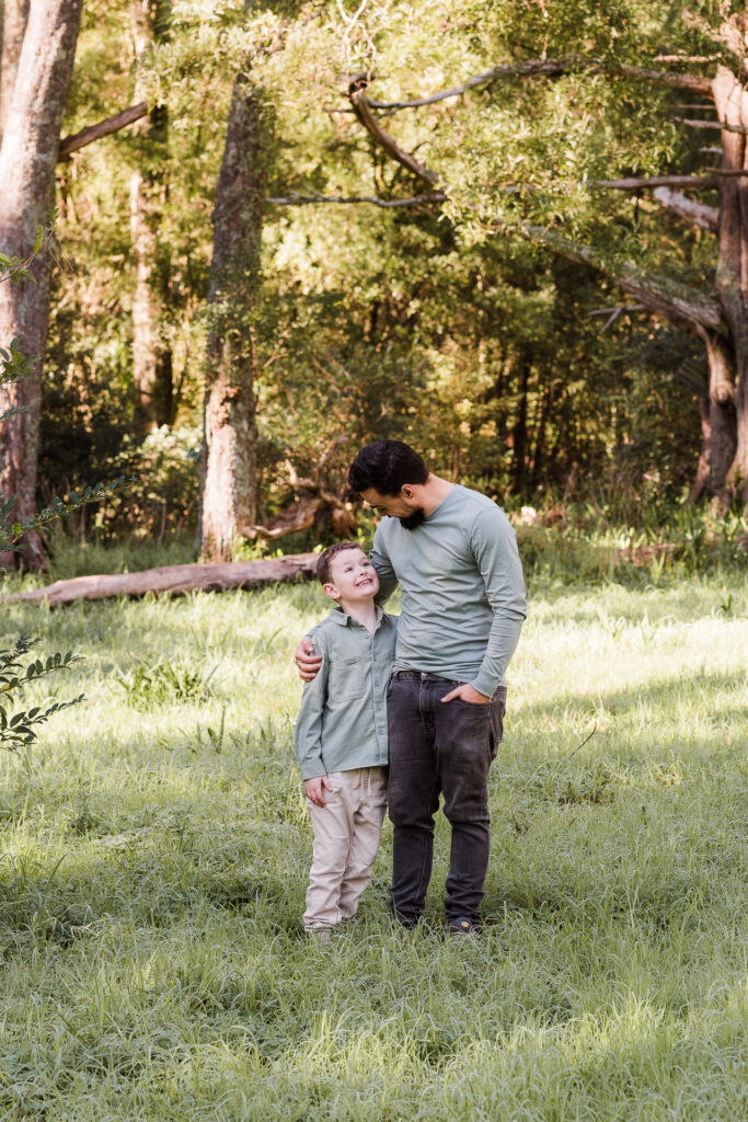 Stepdad kneeling with children in the forest, all sharing a laugh — West Auckland family photographer