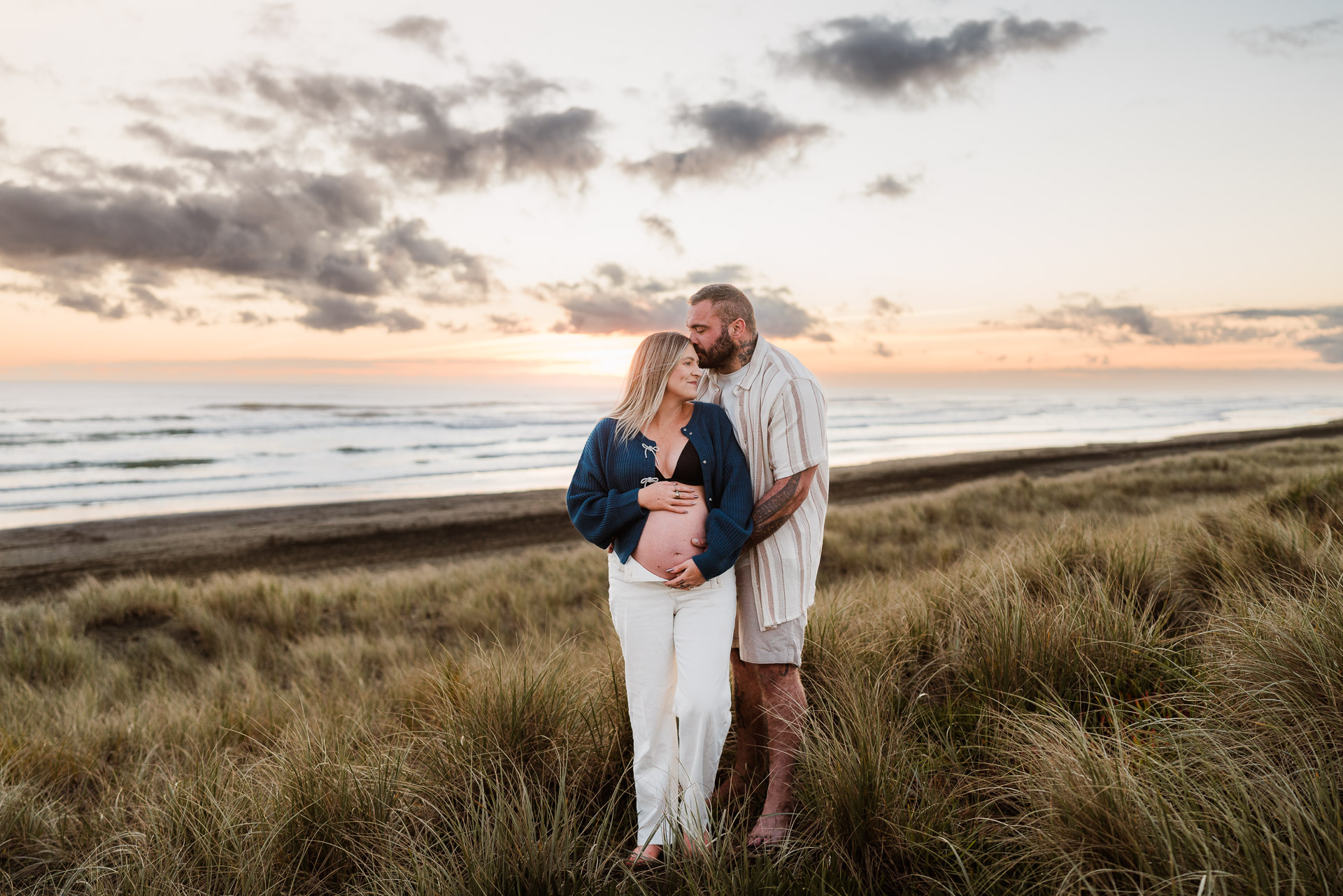 sunset muriwai maternity shoot of mum to be in denim jacket 