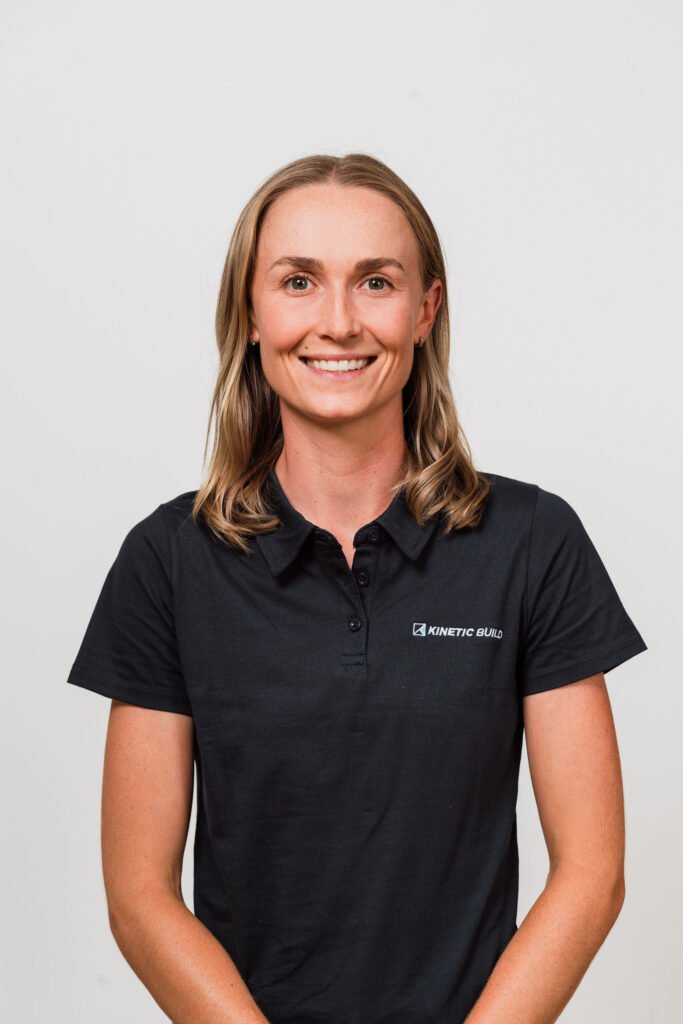 Smiling person in a black Kinetic Build polo shirt against a plain background.